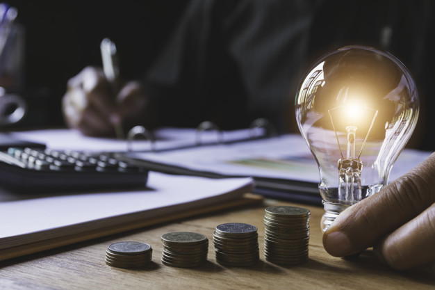 Hand of male holding a light bulb with stack of coins for accoun