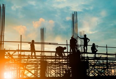 Silhouette of engineer and construction team working safely on scaffolding on high rise building. over blurred background sunset pastel for industry background with Light fair