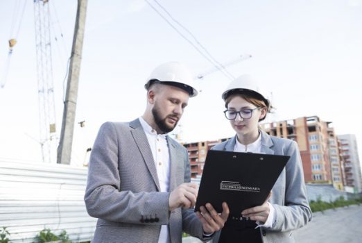 young-female-male-architect-wearing-hard-hat-looking-clipboard_23-2148203935