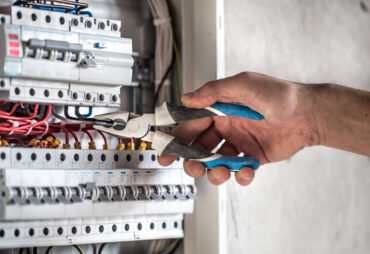 Man, an electrical technician working in a switchboard with fuses. Installation and connection of electrical equipment. Close up.