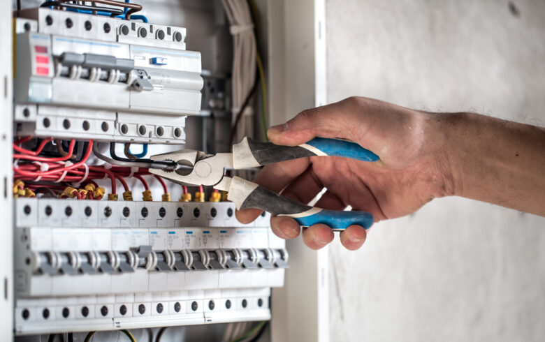 Man, an electrical technician working in a switchboard with fuses. Installation and connection of electrical equipment. Close up.